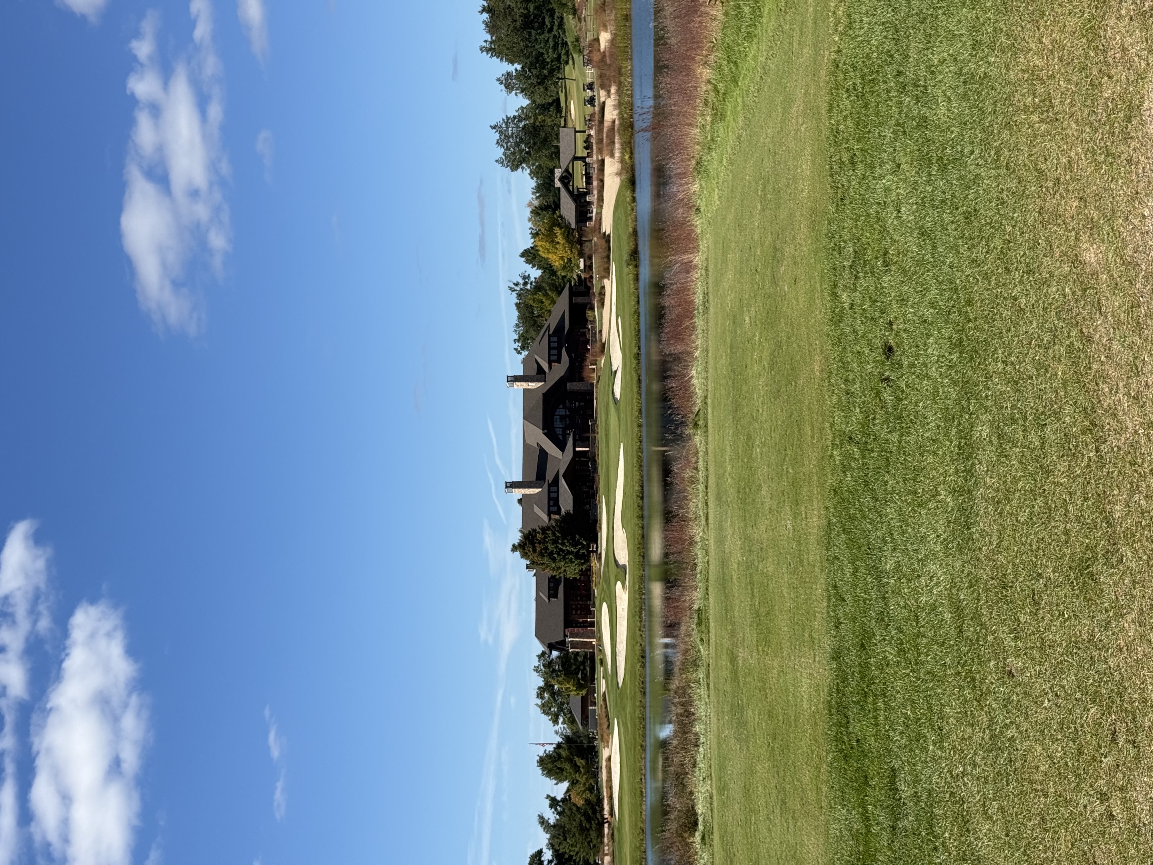 Lodge-style clubhouse behind a pond and white sand bunkers